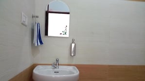 A bathroom with a white sink, a mirror, a towel, and a soap dispenser.