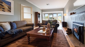 A living room with a fireplace, a sofa, a coffee table, and a bookshelf. - Jesmondene Daylesford (Daylesford)
