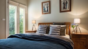 A bedroom with a bed, two nightstands, a window, and two wall-mounted pictures. - Jesmondene Daylesford (Daylesford)