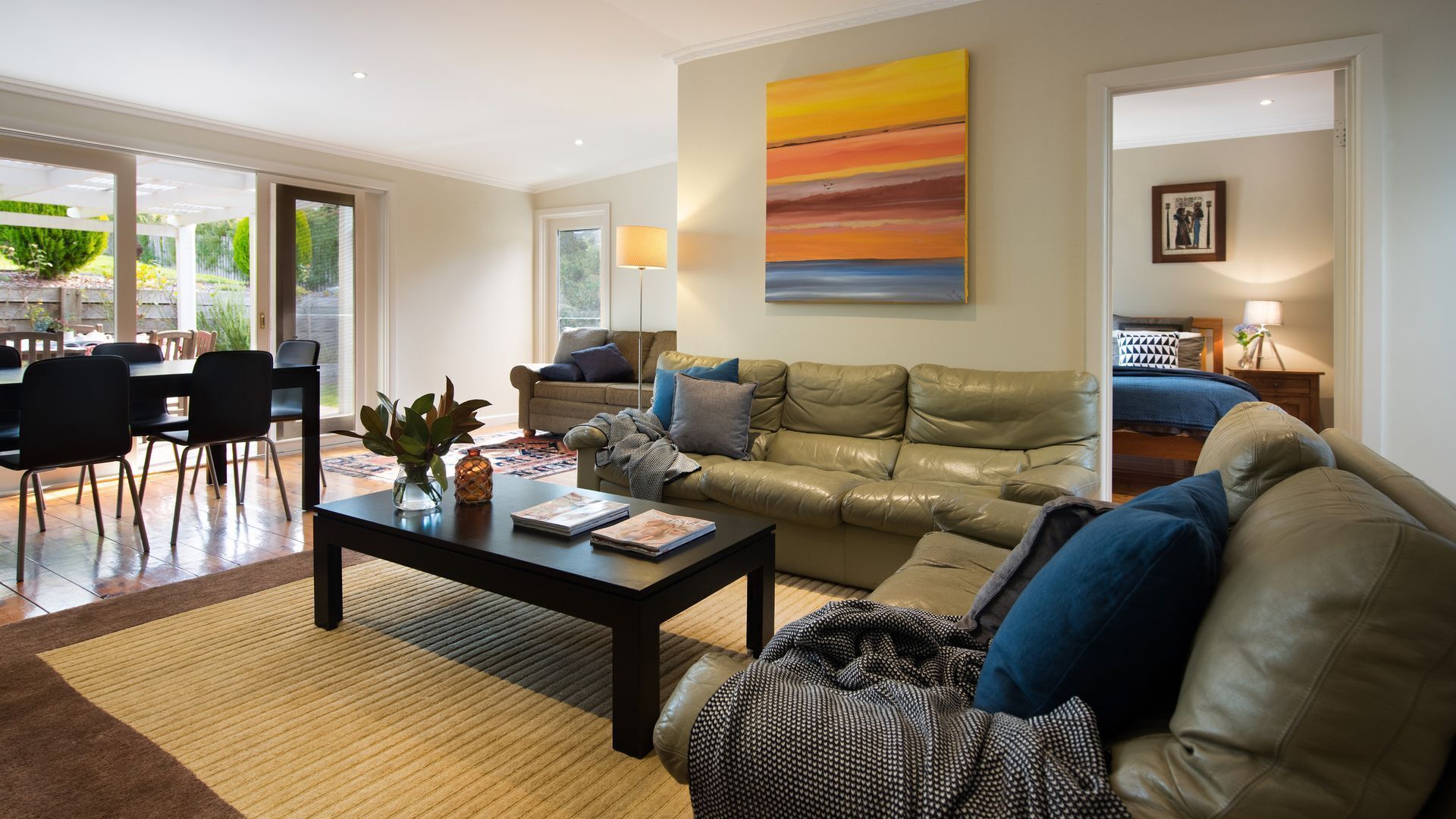 A living room with a leather sofa, a coffee table, and a painting on the wall.