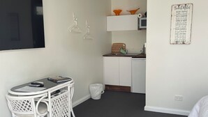A compact hotel room with a dining area, kitchenette, and a bed.