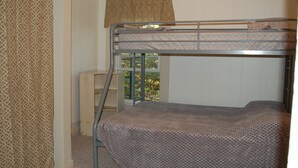 Een stapelbed in een kamer met een patroon gordijn en een raam met uitzicht op bomen.