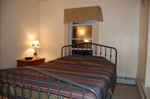 Cozy retreat with a single bed, nightstand, and window with a patterned valance.