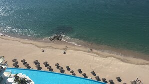Un resort con una amplia piscina, playa y vista al océano.