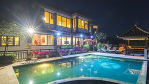 Une maison moderne dotée d’une piscine, d’un espace salon extérieur et de grandes fenêtres bien éclairées.