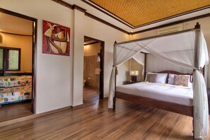 A four-poster canopy bed with a nightstand and lamp, a painting on the wall, and a wooden floor. - Villa Rama Rama – A Huge Private Hilltop Spa Retreat with Stunning Views (Balangan)