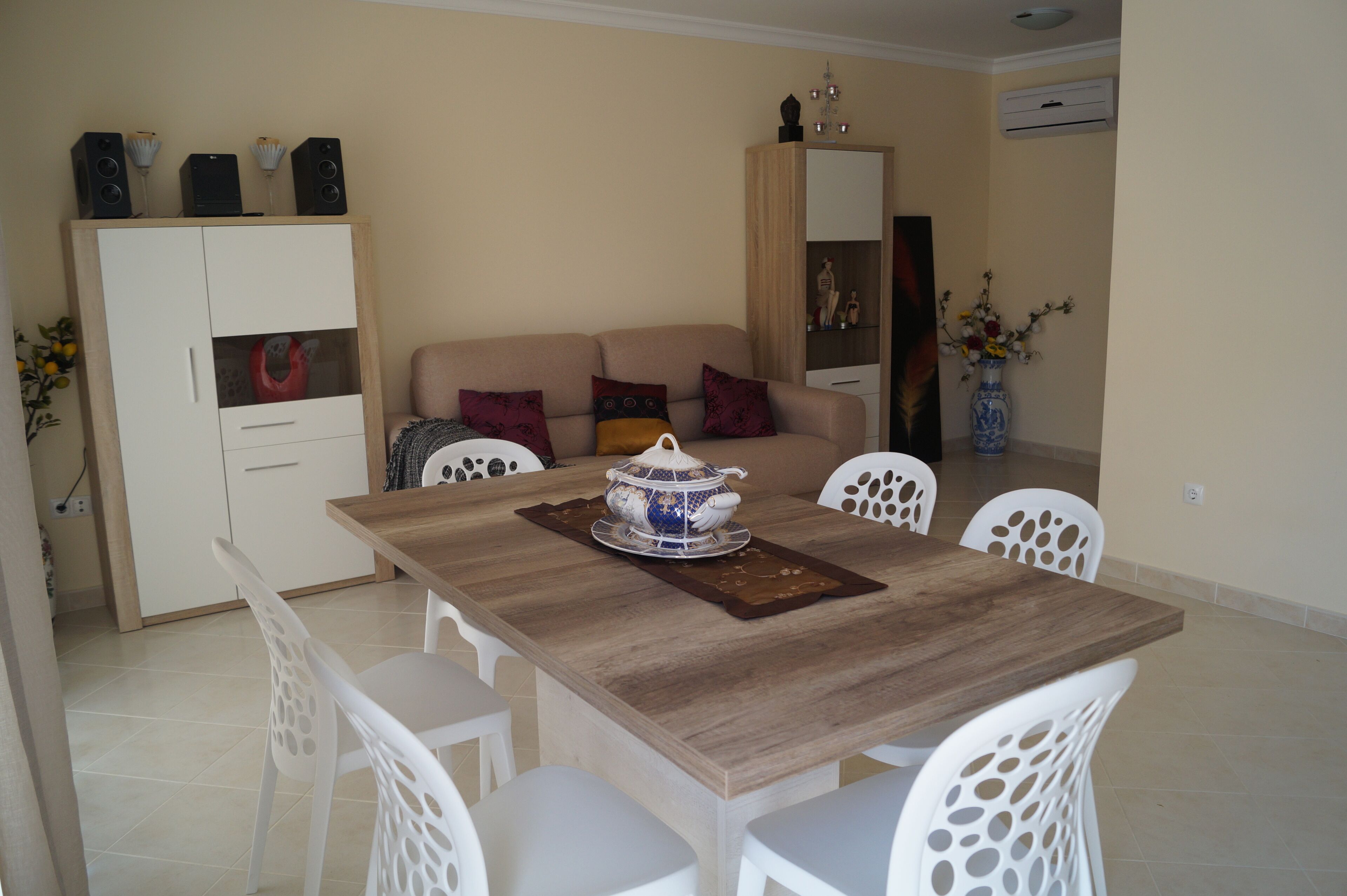 A dining area with a wooden table, white chairs, and a decorative bowl centerpiece.