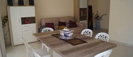 A dining area with a wooden table, white chairs, and a decorative bowl centerpiece.