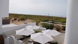 A balcony with white umbrellas and a view of the beach. - SEASIDE VILLA WITH PRIVATE SWIMMING POOL  (Manta Rota)