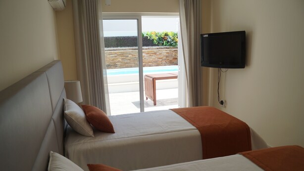 A hotel room with two beds, a TV, and a view of a pool and garden. - SEASIDE VILLA WITH PRIVATE SWIMMING POOL  (Manta Rota)
