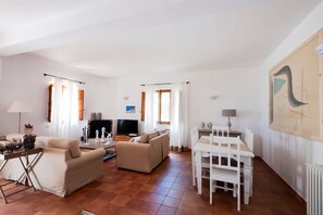 Amplia sala de estar con un sofá, una mesa de comedor y un televisor.
