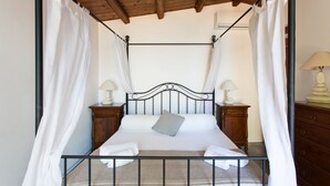 A four-poster bed with white linens, two bedside tables with lamps, and a wooden headboard.
