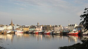 A harbor with boats docked, buildings along the waterfront, and a church spire in the background. - An Airigh  - within walking distance from Stornoway (Stornoway, Isle of Lewis, Scotland)
