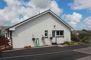 Un bâtiment blanc d’un seul étage, doté d’un toit en pente, d’un petit porche à l’avant et d’une porte bien visible.