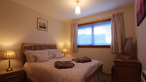A bedroom with a bed, two bedside lamps, a window with curtains, a nightstand, and a dresser. - An Airigh  - within walking distance from Stornoway (Stornoway, Isle of Lewis, Scotland)