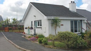 A single-story house with a sloped roof, a front door, and a small porch area. - An Airigh  - within walking distance from Stornoway (Stornoway, Isle of Lewis, Scotland)