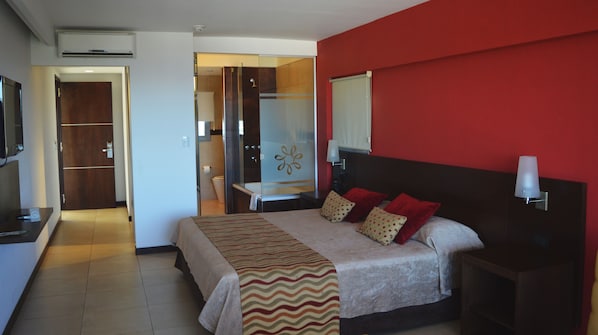 A hotel room with a bed, bedside tables, a desk, and a mirror.