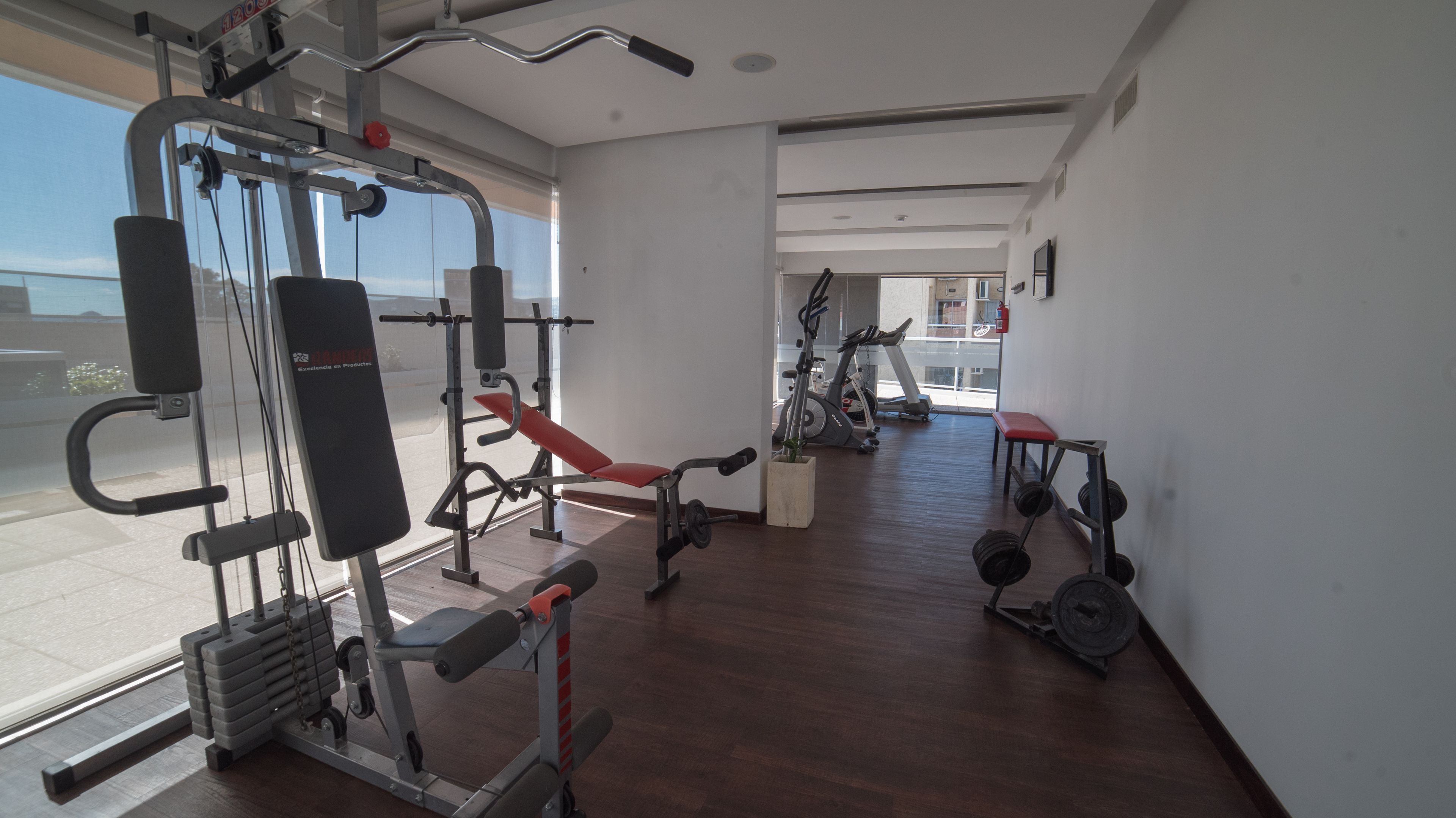 A gym with various exercise equipment, including a bench press, weight racks, and cardio machines.