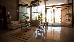 A modern living room with a sofa, coffee table, and a large window. - Hotel Estilo MB (Villa Carlos Paz)