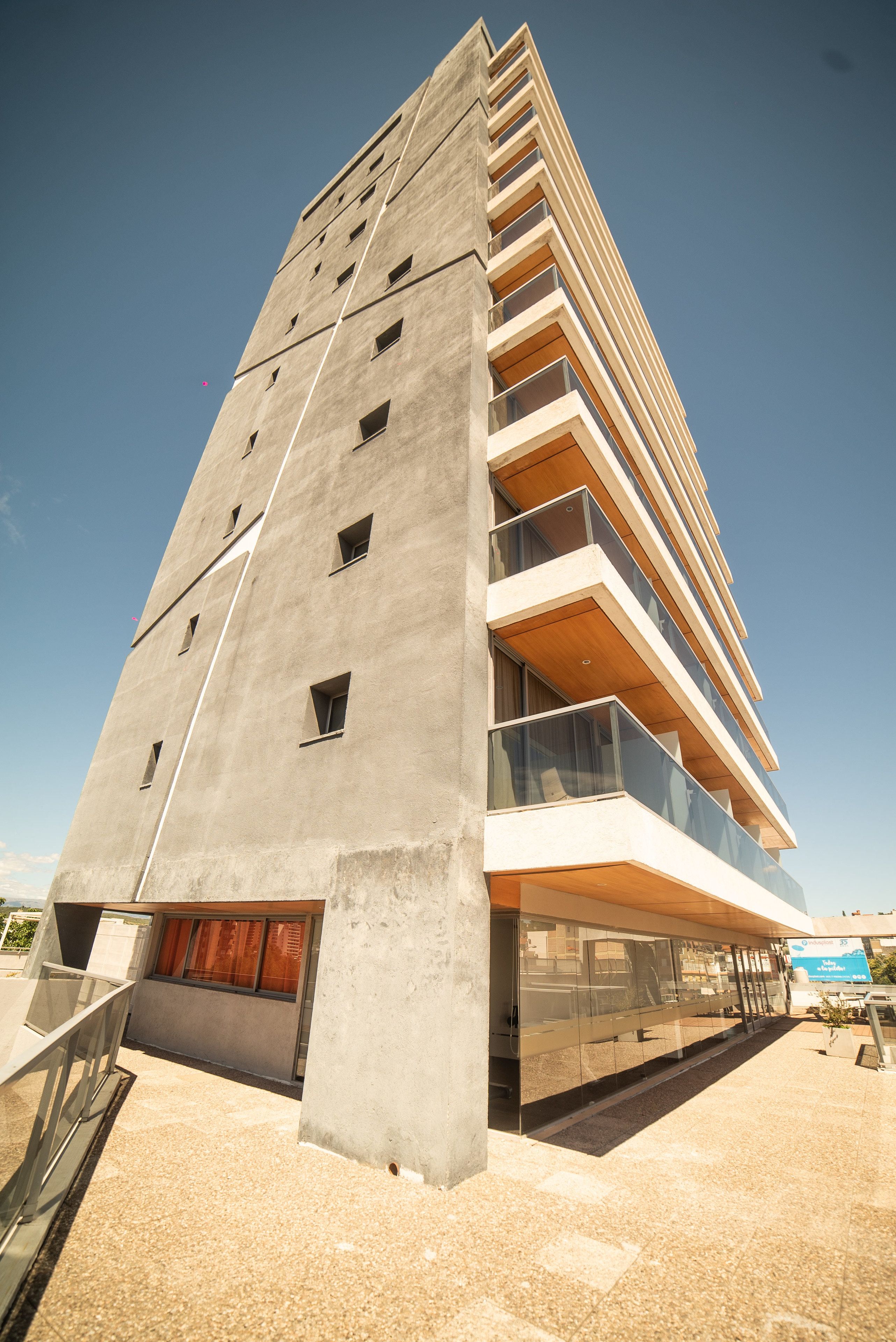 Un edificio moderno de gran altura con varios balcones y fachada de vidrio.