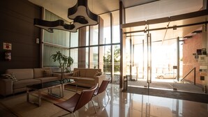 A modern lobby with a sofa, chairs, a coffee table, and a large window with a view of the street. - Hotel Estilo MB (Villa Carlos Paz)