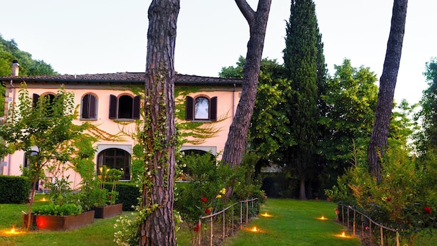 Un jardin avec un sentier, des arbres et un bâtiment doté de fenêtres en arc de cercle.