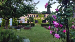 Un jardin avec une pelouse, une table et des chaises, et un bâtiment doté de fenêtres en arc de cercle.