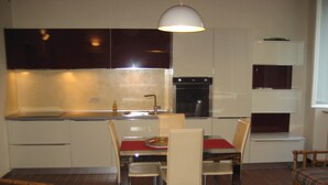Cocina compacta con zona de comedor, que incluye una mesa con sillas, una lámpara colgante y armarios empotrados.