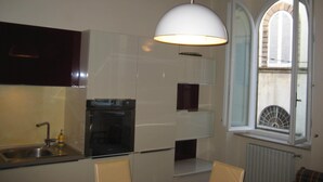 Una cocina con horno empotrado, un lavabo y una ventana con contraventanas.