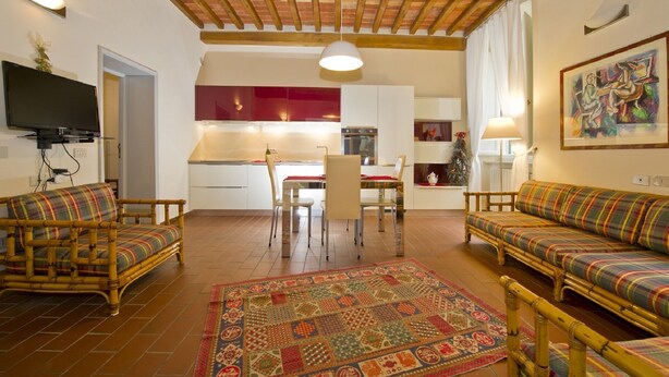 Una sala de estar acogedora con dos sofás, una mesa de comedor y una cocina al fondo.