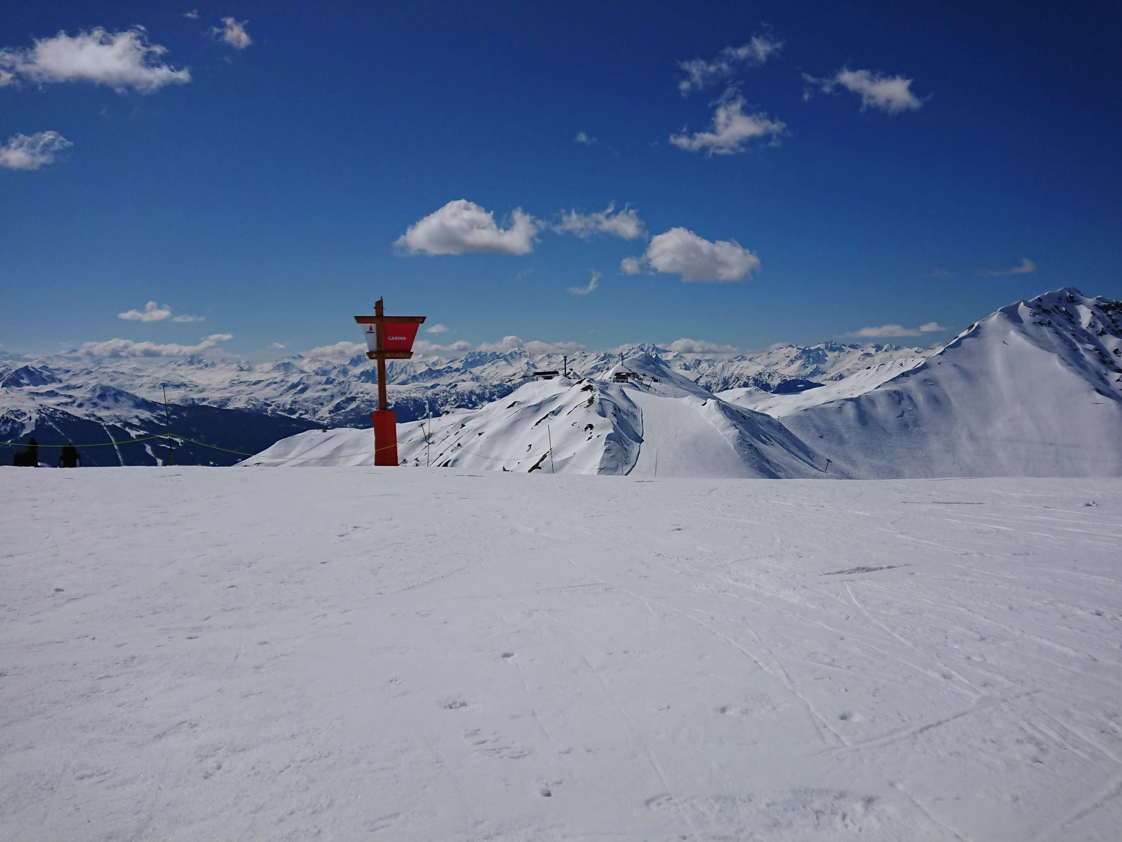 A snow-covered mountain with a signpost and a clear blue sky.