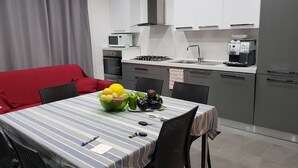 Een kleine keuken met een eethoek, met onder meer een magnetron, fornuis, spoelbak en koffieapparaat.