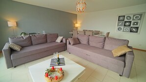 Ein modernes Wohnzimmer mit zwei grauen Sofas, einem weißen Couchtisch und einer Chandelier.