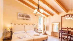 Una camera da letto con due letti, soffitto in legno, un quadro raffigurante un albero e una finestra con tende.