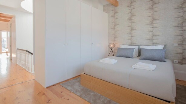 Un dormitorio con una cama grande, un armario blanco y una viga de techo de madera.