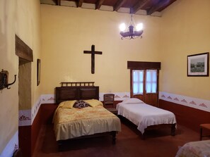 A room with two beds, a wooden cross on the wall, a chandelier, and a framed picture. - Ex-Hacienda San Buenaventura (Tlaxco)