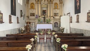 A church interior with wooden pews, a checkered floor, a central altar, and religious artwork on the walls. - Ex-Hacienda San Buenaventura (Tlaxco)