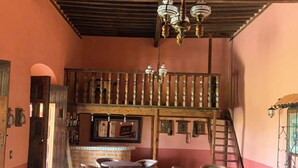 A rustic interior with wooden furniture, a balcony, and a staircase. - Ex-Hacienda San Buenaventura (Tlaxco)