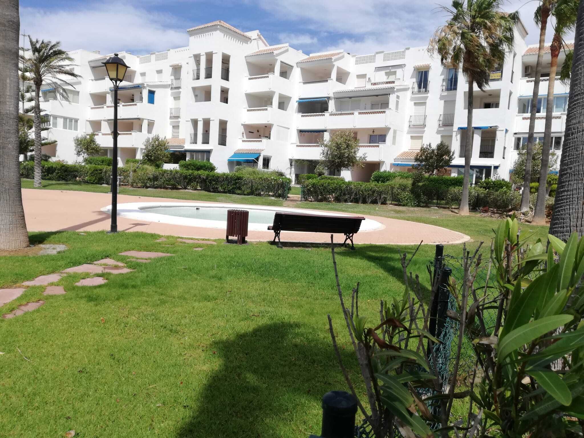 A courtyard with a pool, benches, and a lamp post.