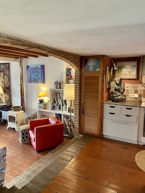 A cozy living room with a red sofa, a fireplace, a bookshelf, and a decorative statue.