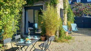 A house with a covered patio, a table with chairs, and potted plants.