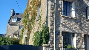 A stone building with ivy on the walls, a street sign, and a clear blue sky.