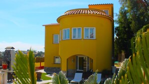 A yellow building with a swimming pool, surrounded by greenery.
