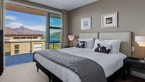 A hotel room with a large bed, two bedside lamps, a view of mountains and a pool through a sliding door. - Remarkable Location – Queenstown (Queenstown)