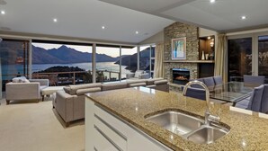 A modern kitchen with a granite countertop, stainless steel sink, and a stone accent wall. - Remarkable Location – Queenstown (Queenstown)