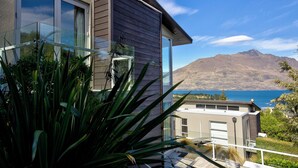 A modern house with large windows, a balcony, and a view of a mountain and lake. - Remarkable Location – Queenstown (Queenstown)