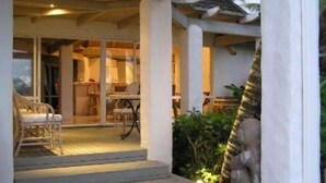 Un espacio al aire libre cubierto con una zona de estar, una escalera que conduce a un espacio interior y vistas de vegetación.