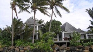 Un resort con edificios de dos pisos, palmeras y una costa rocosa.