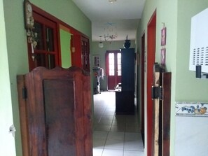 A hallway with a wooden door, a red door, and a tiled floor. - Casa temporada em Paraty Casa Verde (Paraty)