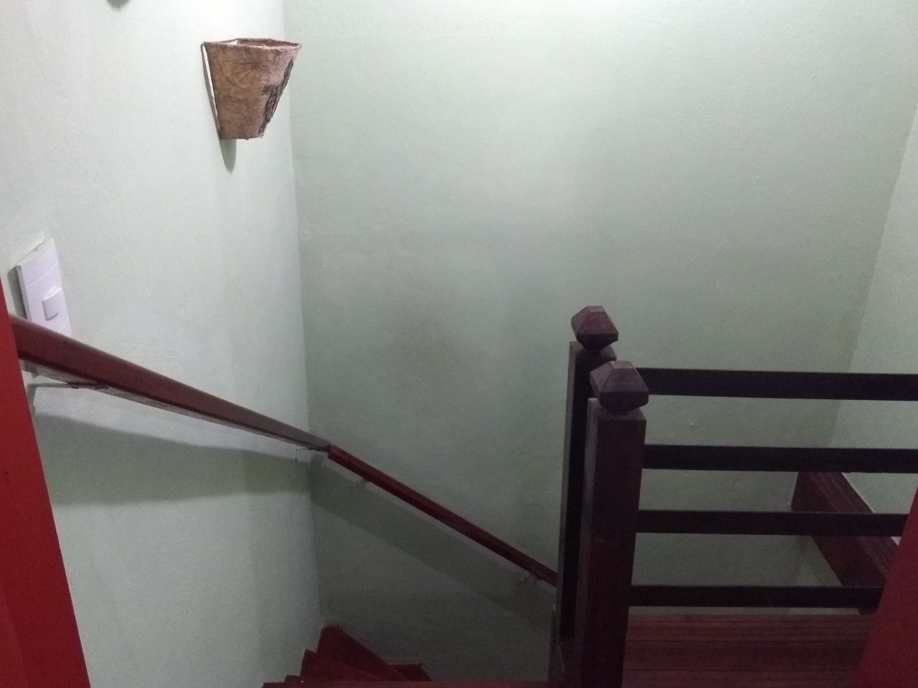 Un escalier avec des rampes en bois et un luminaire fixé au mur.